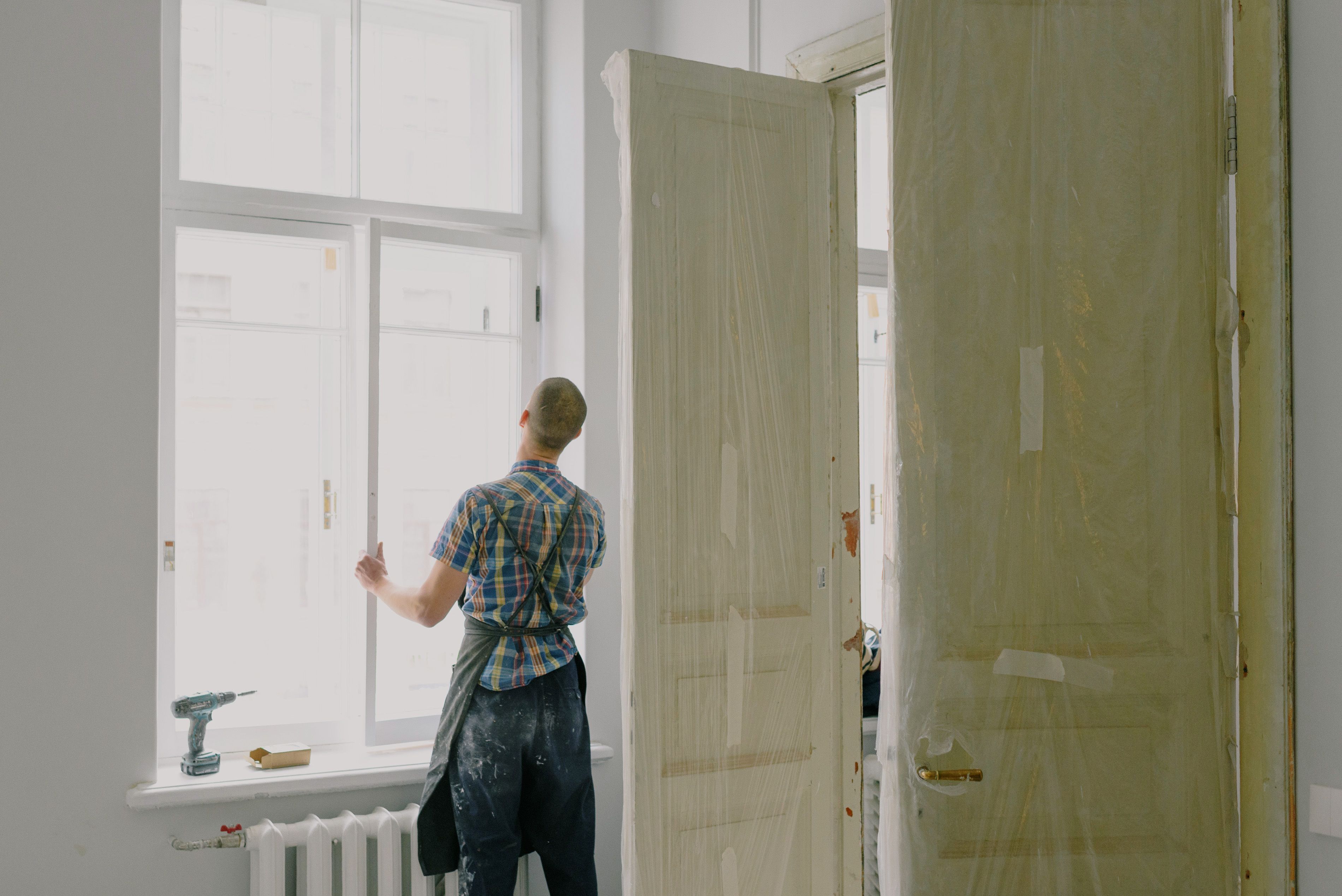 Artisan en rénovation dans un appartement, face à une fenêtre en cours de réfection